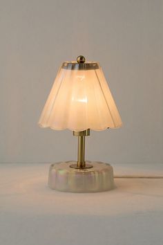 a lamp that is on top of a white table cloth with a light bulb turned on