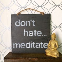 a wooden sign that says don't hate meditate next to a buddha statue