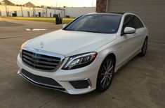 a white mercedes s - class parked in front of a garage