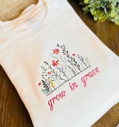 Grow in Grace embroidered Sweatshirt Fit: Unisex, Fits loose/relaxed/Crewneck Sizing: S,M,L,XL,2XL Material: 50% Cotton, 50% Polyester Thread colors are as shown *TURN AROUND TIME ~Shirts are made to order, please allow 5-7 business days to make your order (plus ship time).  *Colors and Text  We have done our best to represent colors accurately. PLEASE NOTE: Due to the hand crafted nature, and monitor displays, please expect a slight variation in colors. We will use the EXACT spelling you provide for the name. Please double check your personalization before submitting your order.  * If this is being shipped directly to the recipient I can place a small personalized note with the gift.  Please let me know what you want it to say in the check out. I don't accept returns, exchanges, or cancel Embroidered Cotton Crew T-shirt, Embroidered Cotton Crew Top, Fall Cotton T-shirt With Floral Embroidery, Spring White Sweatshirt With Custom Embroidery, White Sweatshirt With Custom Embroidery For Spring, White Custom Embroidered Sweatshirt For Spring, Crew Cotton Top With Machine Embroidery, Cotton Crew Top With Embroidered Text, Cotton Crew Top With Machine Embroidery