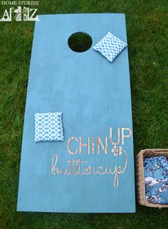 a blue cornhole game set up in the grass with pillows and other items on it