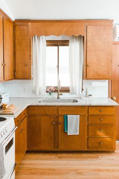 a kitchen with wooden cabinets and white counter tops, along with a window over the sink