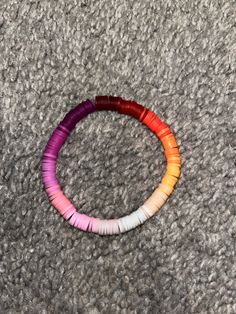 three different colored bracelets sitting on top of a gray carpeted floor next to each other