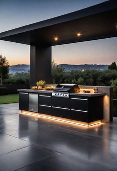 an outdoor kitchen is lit up at night with lights on the counter and grill area