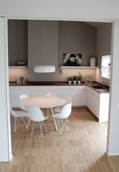 a white table and chairs in a small room with wood flooring on the other side