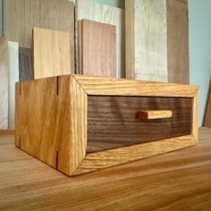 a wooden box sitting on top of a table next to other wood pieces in different colors