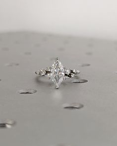 a diamond ring sitting on top of a silver surface with drops of water around it