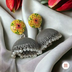 Add a touch of sunshine to your look with these stunning oxidised silver earrings with yellow flower. The delicate silverwork perfectly frames the vibrant yellow flower, which is sure to turn heads. The flower itself is beautifully detailed, with delicate petals and a central cluster of stamens. The yellow color is bright and cheerful, and it is sure to brighten up any outfit. These earrings are perfect for any woman who wants to add a touch of glamour to her look. They can be worn for a special occasion, such as a wedding or a cocktail party, or they can be dressed down for a more casual look. Features: Beautiful silverwork and yellow flower design Delicate and detailed petals and stamen Bright and cheerful yellow color Perfect for any occasion Materials: Oxidised Silver Yellow resin flow Traditional Flower Earrings For Festive Occasions, Yellow Bohemian Earrings For Festive Occasions, Yellow Temple Jewelry Earrings For Festivals, Yellow Danglers For Festive Occasions, Yellow Danglers As A Gift, Festive Yellow Meenakari Danglers, Yellow Meenakari Earrings For Festive Season, Yellow Temple Jewelry Jhumkas For Festivals, Diwali Gift Yellow Jhumkas