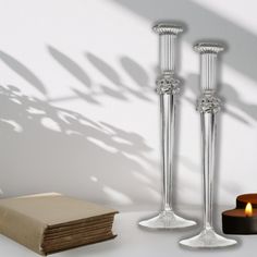 two tall candlesticks sitting on top of a table next to a stack of books