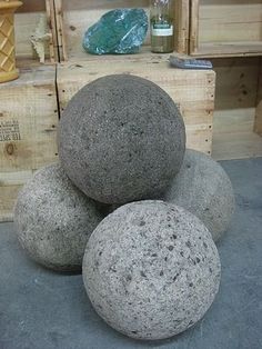 three gray rocks sitting on top of each other in front of wooden boxes and vases