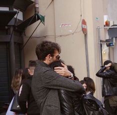 two people hugging each other on the street