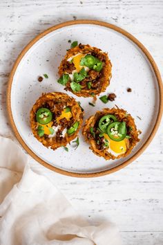 three small appetizers on a white plate with green peppers and cheese, ready to be eaten