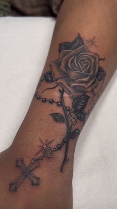 a rose and cross tattoo on the arm with rosarys attached to it's wrist