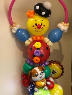 a bunch of balloons that are in the shape of clowns and cats hanging on a wall