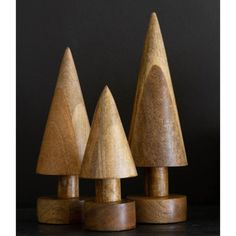 three wooden toy trees sitting on top of a black table next to eachother