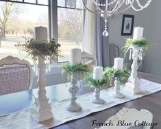 a dining room table with candles, flowers and greenery on the centerpieces