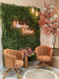 two chairs sitting next to each other in front of a wall with plants on it