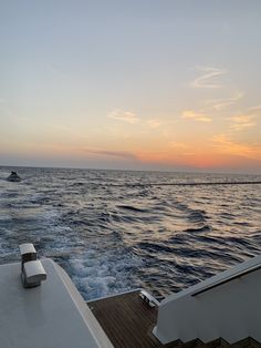 the sun is setting over the ocean as seen from a boat on the water in the distance