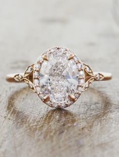 an oval shaped diamond ring on top of a wooden surface