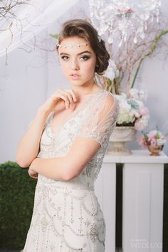 a woman in a white dress is posing for a photo with her hands on her chin