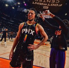 two basketball players are standing on the court and one is holding a water bottle in his hand