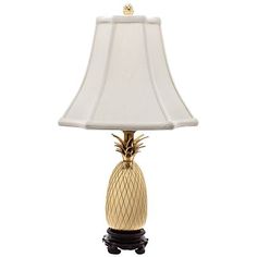 a gold pineapple lamp with a white shade on the bottom and black base, against a white background