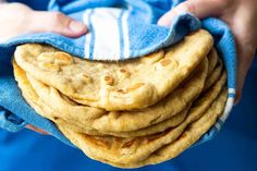 a stack of pita bread on top of a blue towel in someone's hands