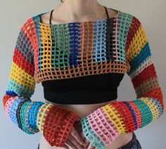 a woman with her hands in her pockets wearing colorful crochet knitted gloves