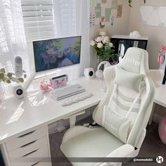 a white computer chair sitting in front of a desk with a monitor and keyboard on it