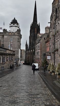 a person walking down a cobblestone street in an old city with tall buildings