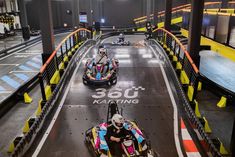 two go kart racers racing down an indoor track