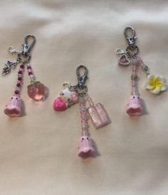 three charms are attached to each other on a white surface with flowers and hearts hanging from them