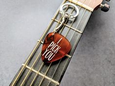 a guitar pick keychain with the words pink you on it sitting on top of an electric guitar