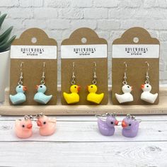 three little rubber ducks are sitting in front of some earrings