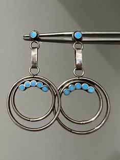 For your consideration, impressive vintage Zuni Native American sterling and turquoise earrings. Each earring contains a dangling round double loop patterns decorated with snake eye turquoise inlay.  These are in excellent vintage condition.  These are unsigned as was normal for earlier works. Metal tested for silver. These were lightly hand polished with cloth and have some patina and minor abrasions to the metal. These are also handmade and may not be perfectly symmetrical etc.  These measure approx 1 3/4" long and are  fairly lightweight and weigh 5.6 grams togeather. Very comfortable pair to wear all day long.  Amazing handmade Native American jewerly great to add to any collection or great for gifting! Vintage Turquoise Round Earrings, Retro Round Pierced Jewelry, Turquoise Clip-on Round Jewelry, Turquoise Round Clip-on Jewelry, Retro Round Turquoise Jewelry, Retro Turquoise Jewelry, Snake Eyes, Eye Earrings, Vintage Turquoise