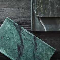 a green marble plate sitting on top of a wooden table next to a metal box