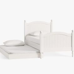 a white bed sitting next to a pillow on top of a wooden headboard and foot board