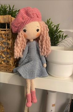 a crocheted doll sitting on top of a shelf next to a wicker basket