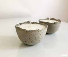 two cement bowls with white candles in them