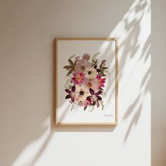 a painting hanging on the wall next to a vase with flowers in it and a shadow