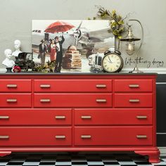 a red dresser with many drawers and clocks on top