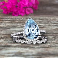 an aqua blue and white topazte ring on a wooden surface with flowers in the background