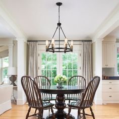 a dinning room table with four chairs and a chandelier hanging from the ceiling