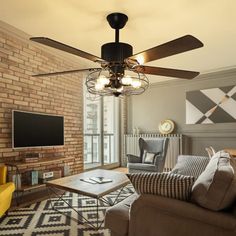 a living room with a couch, coffee table and ceiling fan in front of a flat screen tv