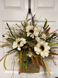 a basket filled with white flowers sitting on top of a door