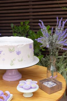 there is a cake on the table with cookies and lavenders in front of it