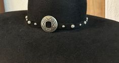 Add a classy look to your hat! This hatband has a Silver Concho with a series of silver spots all the way around it, on a strip of leather, a simple design to give it a more genuine old west look. It is hand done and adjustable by the leather in the back.  It is shown on a hat so you can see how it looks.  The concho measures about 1.5" in diameter.  It measures approximately 22" with stud / spot adornment.  Length is adjusts by ties on the back.  Thank you for looking!      Made in the USA! Old West, Hat Band, How To Look Classy, Simple Design, Cowboy Hats, Simple Designs, Caps Hats, Accessories Hats, The Way