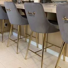 four grey velvet bar stools with gold legs in front of a kitchen countertop