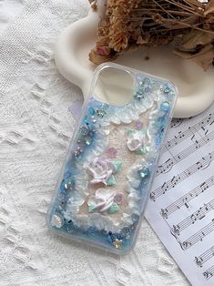 an iphone case with shells and seashells on it sitting next to music sheets