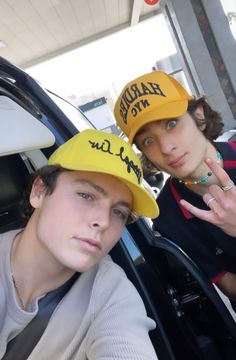 two people wearing hats standing next to each other in front of a car with the door open